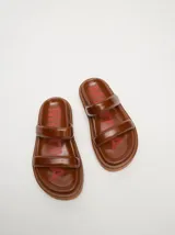 Sandalias de cuero vacuno color marrón con acabado brillante, diseño de dos tiras anchas acolchadas y plataforma baja.