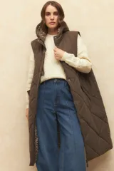 Chaleco largo marrón capitoneado con capucha, cierre frontal y bolsillos laterales. Forro interno de satén con estampado animal print.