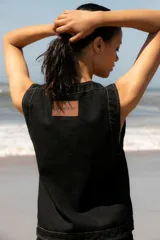 Chaleco de denim negro sin mangas con cuello redondo y costuras en contraste. Presenta un parche de cuero marrón en la parte posterior con el logo de la marca Be Ganesha. Confeccionado en tejido de algodón.