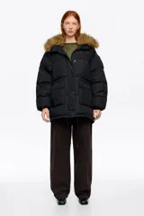 Campera tipo plumífero de largo medio y corte recto en tejido técnico, con cierre frontal, capucha con borde de pelo sintético desmontable y bolsillos frontales con solapa.