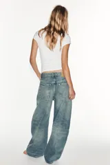 Jeans de tiro medio y corte balloon color azul, con trabillas, bolsillos delanteros y traseros, y cierre frontal con cremallera y botón metálico.