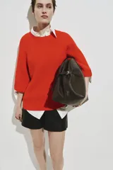Top de punto acanalado color naranja, con cuello redondo, mangas al codo de corte raglán y diseño oversized. Presenta terminaciones acanaladas en cuello, puños y bajo.