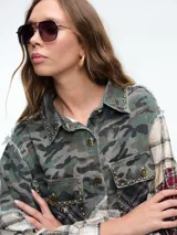 Chaqueta larga tipo camisa con diseño patchwork, confeccionada mediante la combinación de diversos tejidos de algodón con estampados de cuadros, tartán y motivos florales. Presenta cierre frontal con botones, cuello clásico, bolsillos delanteros con solapa y bordes deshilachados.
