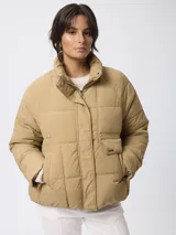 Campera puffer de nylon color negro, con cuello alto, cierre frontal con cremallera y botones a presión. Presenta bolsillos frontales con solapa y diseño acolchado.