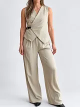 Conjunto de dos piezas para mujer en color beige, compuesto por un chaleco cruzado sin mangas con cinturón lateral y un pantalón de corte amplio.