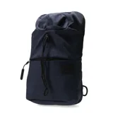 Mochila pequeña de diseño urbano en color azul marino con textura jaspeada. Cuenta con un compartimento principal con cierre de cordón ajustable, un bolsillo frontal con cierre y una etiqueta decorativa con logo en el frente.