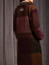 Chaquetón largo de paño con diseño de cuadros en tonos tierra, borravino y negro. Presenta cuello solapa, bolsillos laterales y forro interior.
