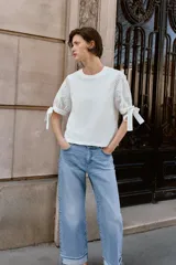 Camiseta de cuello redondo confeccionada en algodón, con mangas cortas abullonadas de tejido bordado perforado y detalle de lazadas en los puños.