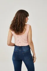 Musculosa rosa con estampado de margaritas blancas y amarillas, de bretel ancho, corte al cuerpo y cuello redondo.