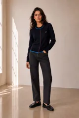 Cardigan de punto azul con ribetes en contraste negro, cuello redondo, cierre frontal con botones y bordado pequeño en el pecho.