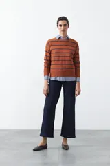 Sweater de tejido de punto con diseño de rayas horizontales en tonos bordó y rojo. Presenta cuello redondo, mangas largas con hombros caídos y terminaciones acanaladas en puños, cuello y ruedo.
