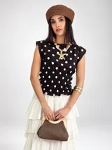 Blusa sin mangas de viscosa color negro con estampado de lunares blancos, cuello redondo y cintura fruncida con elástico.