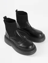 Botas negras de cuero sintético con caña elastizada y suela track.