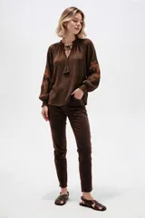 Pantalón jean skinny de calce medio, color marrón oscuro, con diseño clásico de cinco bolsillos.