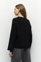 Sweater de tejido de punto color gris melange, con cuello redondo y diseño de franjas horizontales en relieve. Presenta mangas largas acampanadas y un corte holgado.