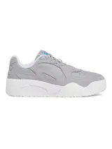 Championes Under Armour modelo Court Anatomix, color gris con detalles en blanco. Presentan una parte superior de gamuza resistente con revestimientos sintéticos, entresuela de EVA acolchada y suela de goma gruesa para mayor tracción.