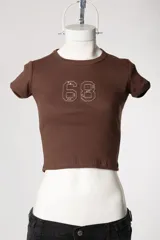 Baby tee de calce al cuerpo y manga corta, con cuello redondo y diseño con tachas frontales.