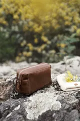 Neceser de cuero color marrón con cierre superior de cremallera metálica y asa lateral.