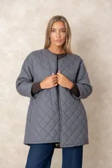 Campera acolchada de diseño capitoné en color gris, con cuello redondo, cierre frontal y mangas largas. Presenta un interior estampado que se revela al remangar las mangas.