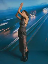 Vestido largo negro con escote drapeado tipo halter y falda transparente.