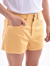 Short de jean color amarillo, de tiro medio con cierre y botón frontal, bolsillos laterales y traseros, y ruedo deshilachado.