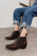 Botín negro de cuero con elásticos laterales, taco bajo y tirador trasero.