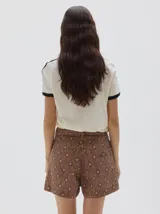 Short tiro alto color marrón con estampado de cuadros en tonos beige y azul oscuro. Presenta cortes verticales en la parte delantera y desgaste en las costuras.