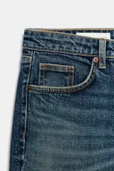 Jeans de tiro alto con diseño de cinco bolsillos y corte cropped flare. Presenta un acabado deshilachado en el bajo y cierre frontal con cremallera y botón metálico.