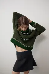Jersey de punto con cuello subido y manga larga, diseño de jacquard con motivos geométricos en tonos verdes y crema.