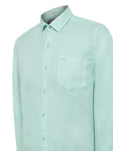 Camisa de manga larga confeccionada en 100% lino orgánico, color verde menta. Presenta cuello clásico, cierre frontal con botones, puños abotonados y un bolsillo en el pecho con el logo de la marca bordado.