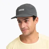 Gorro tipo gorra de cinco paneles Merrell, color gris grafito, con visera plana y paneles laterales perforados para mayor ventilación. Incluye parche con logo de la marca en el frente.