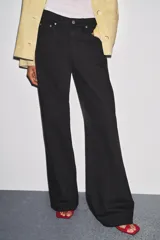 Jeans de tiro bajo, pierna ancha y largo completo, color negro. Presenta cinco bolsillos y cierre frontal con cremallera y botón metálico.