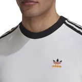 Remera blanca de algodón con cuello redondo y mangas cortas con ribete negro. Presenta las tres rayas características de Adidas en color negro en los hombros y el logo de la marca bordado en el pecho.