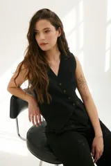 Chaleco negro con botones diagonales y tela bordada.