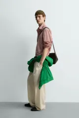 Camisa de algodón con cuello solapa, manga larga terminada en puño con botón y cierre frontal de botonadura. Presenta un patrón de cuadros en tonos rojo y beige.