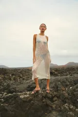 Vestido largo sin mangas, de corte amplio y confeccionado en lentejuelas color plateado.