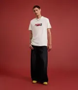 Remera de algodón color blanco, corte comfort, con cuello redondo y manga corta. Presenta un estampado grande en la espalda con un auto de carrera estilo Fórmula 1, un diagrama de circuito y varios textos gráficos relacionados con carreras.