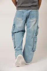 Pantalón de jean estilo baggy cargo, color azul claro con efecto lavado. Presenta bolsillos laterales tipo cargo en los muslos, corte holgado y diseño de pierna ancha.