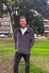 Buzo de pana gris oscuro con cuello alto y cierre frontal parcial de cuarto. Posee bolsillos frontales tipo canguro y diseño holgado de manga larga.