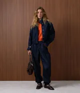 Pantalón de jean estilo aladín con cintura alta y pretina estructurada. Presenta pinzas frontales, volumen en la cadera y piernas con entalle progresivo que finalizan en puños con elástico, logrando un efecto jogger sofisticado.