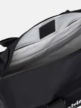 Bolso deportivo tipo duffle bag de color negro, confeccionado en poliéster. Presenta asas de mano y una correa ajustable para llevar al hombro. En el centro tiene un bolsillo frontal con cierre donde se lee el logo de Calvin Klein en blanco, incluyendo las direcciones "West 39th Street" y "New York City".