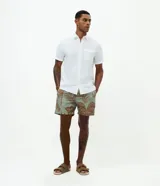 Bermuda de baño masculina confeccionada en microfibra, con estampado de palmeras y trancadero. Presenta cintura elástica con lazo de ajuste, bolsillos laterales y forro interno de malla.