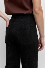 Pantalón de jean corte wide leg color negro, con sutiles detalles de brillo en toda la superficie. Presenta tiro alto, cierre frontal con botón y bolsillos laterales.