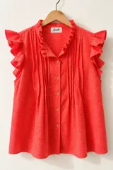 Blusa de diseño cuadrillé en color rojo y blanco, sin mangas, con volados en el cuello mao y en los hombros. Cuenta con alforzas verticales en el frente y cierre frontal de botones.