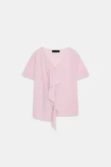 Top de punto rosado con escote en V y manga corta, decorado con un volante asimétrico en la parte delantera.
