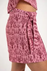 Short pollera color rosa con estampado abstracto en tonos borgoña y lazo lateral.