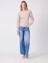 Buzo de tejido lurex marca Nanette, con cuello redondo y mangas largas con diseño plisado. Presenta puños ajustados con aplique de botones decorativos.