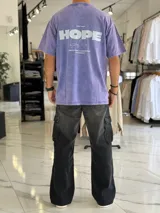 Remera oversize gris con efecto gastado, mangas cortas y estampa con texto blanco en el frente y en la espalda.