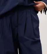 Pantalón de poliamida color azul marino, con diseño barrel de piernas anchas, cintura estructurada con pasacintos y pinzas frontales. Cuenta con botamanga levemente ajustada.