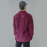 Camisa de pana azul con corte oversize, cuello clásico, cierre frontal de botones y dos bolsillos con solapa en el pecho.